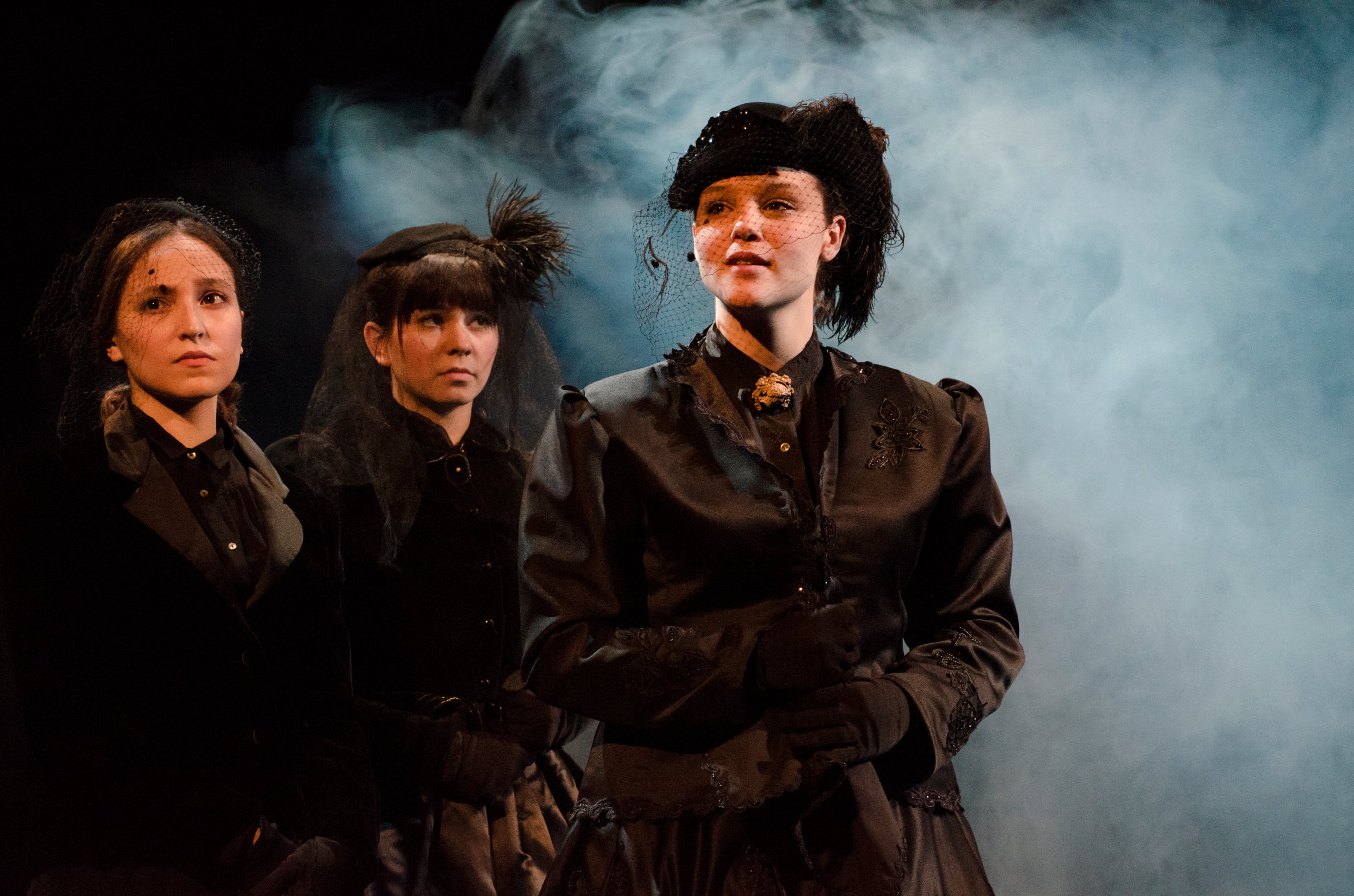 Three women dressed in funeral garb looking mournful