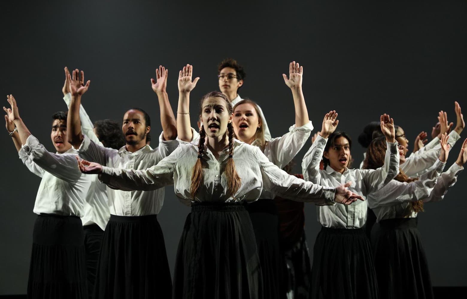 Actors in matching garb with arms raised