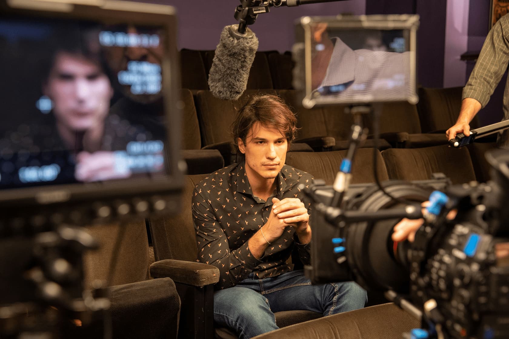 A video-camera records actors sitting around a table