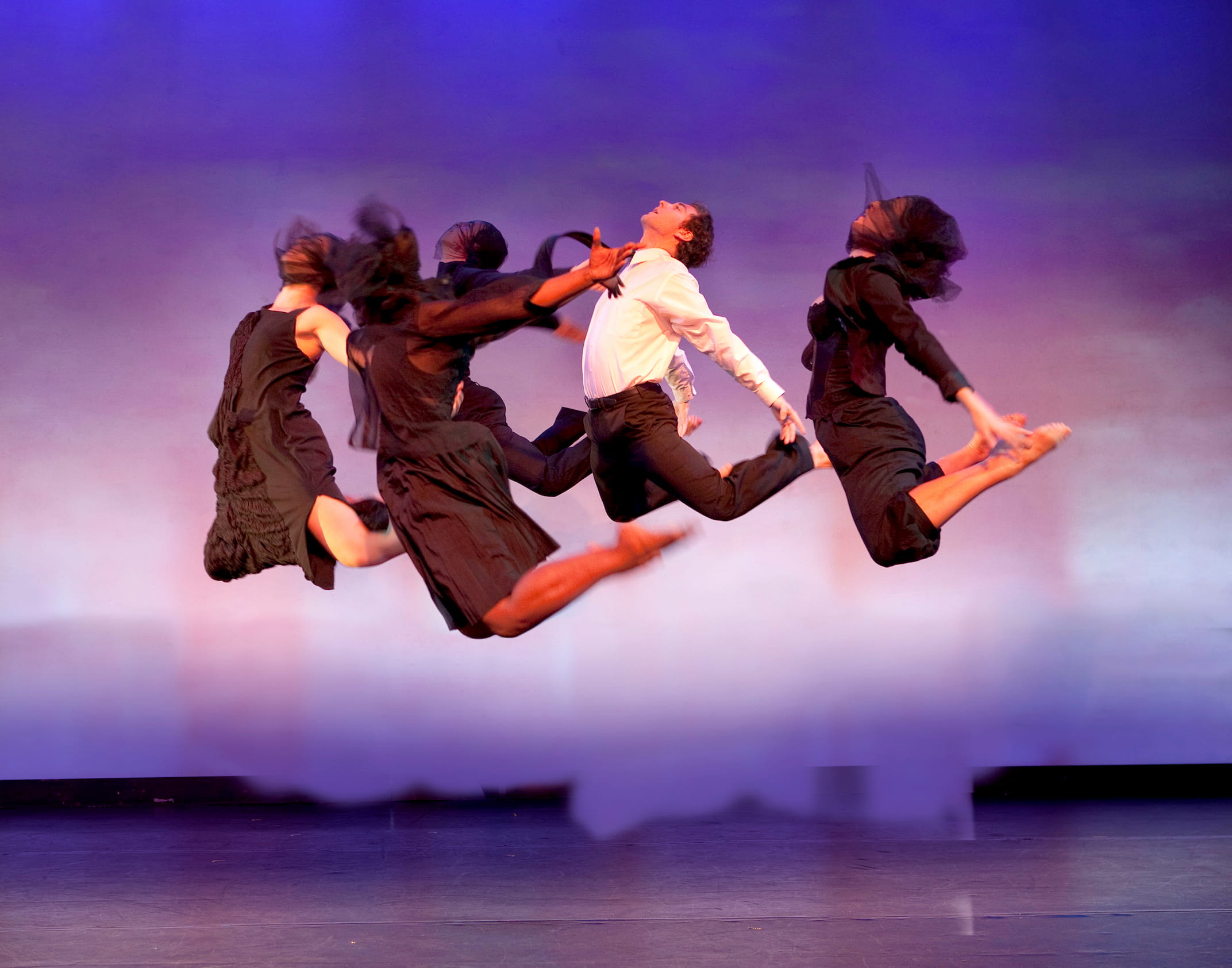Five formally dressed dancers defy gravity in a synchronized jump