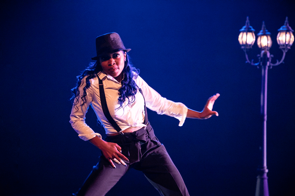 A dancer pops and glides into a dance move with a streetlamp in the background