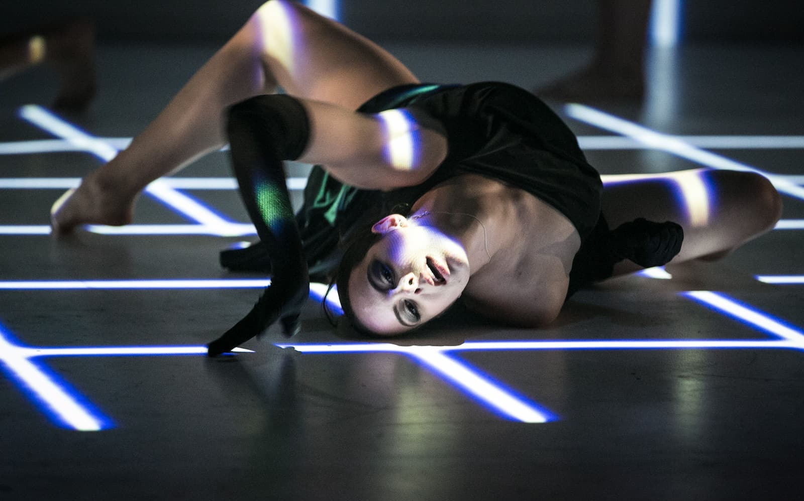 A dancer is sprawled out across the stage mid-roll