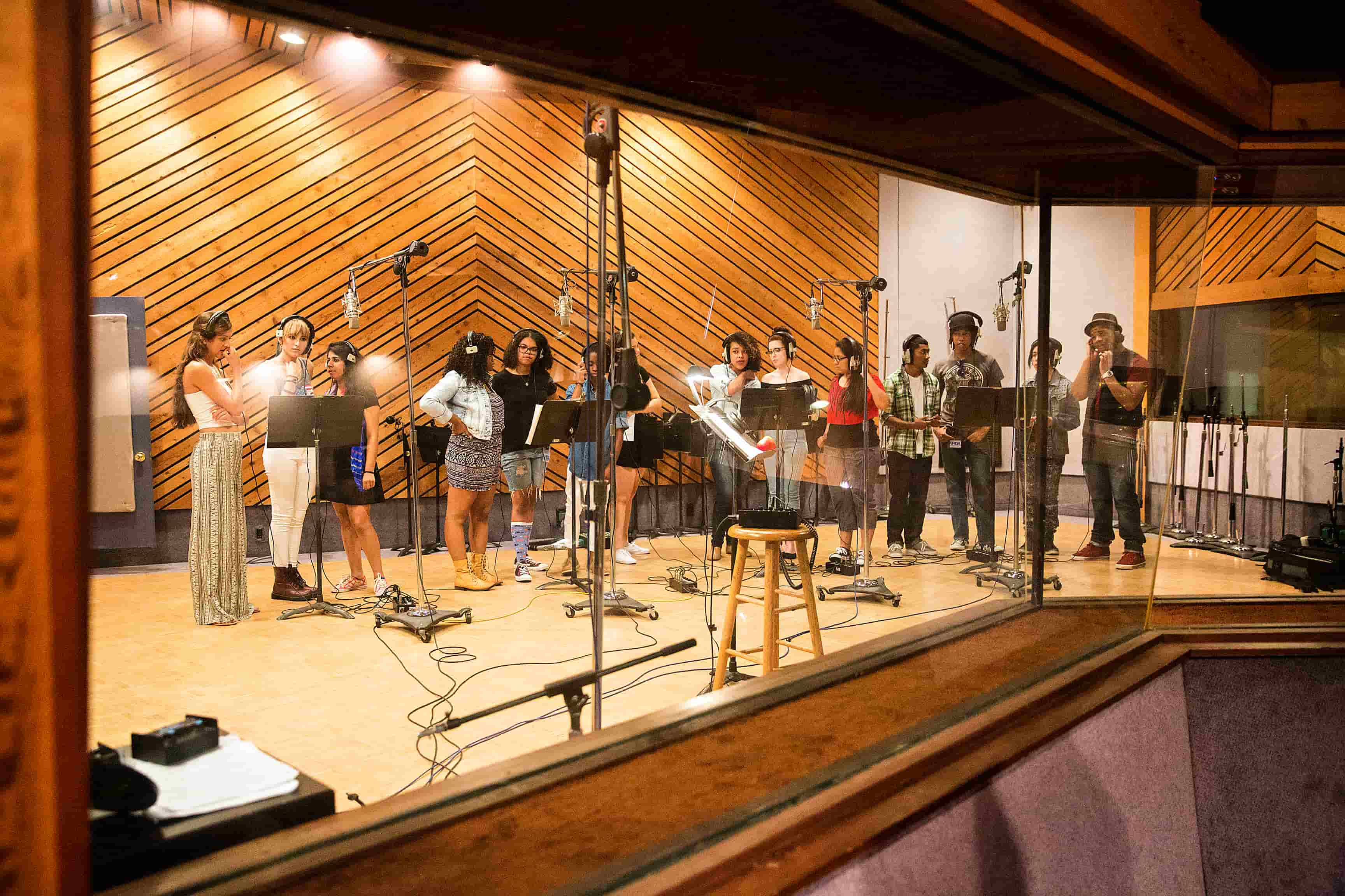 A diverse group of individuals collaborating in a professional recording studio, working on music production and sound engineering.